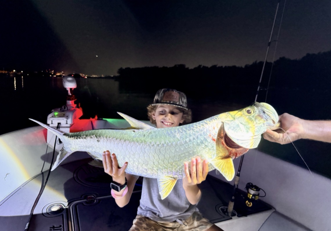 10-year-old angler holding a tarpon during a father-son fishing trip in Fort Lauderdale with Lunkerdog Charter Fishing.