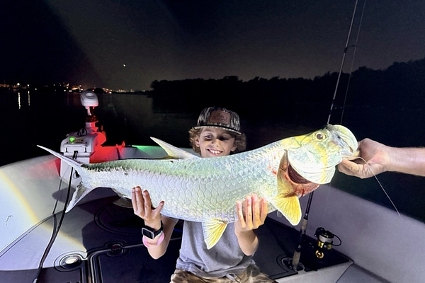 10-year-old angler holding a tarpon during a father-son fishing trip in Fort Lauderdale with Lunkerdog Charter Fishing.